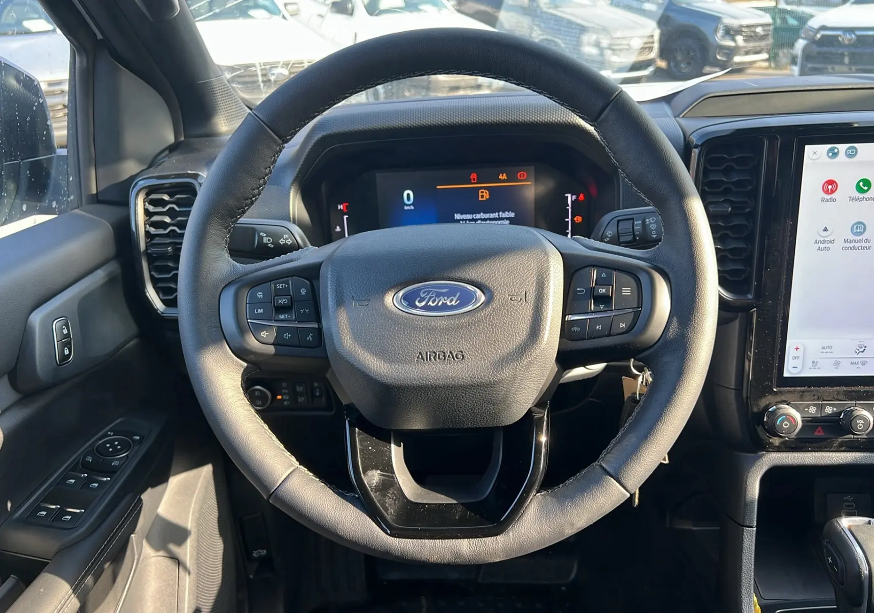 Vue intérieure centrée sur le volant cuir multifonctions du Ford Ranger 2025 avec tableau de bord numérique et écran tactile.