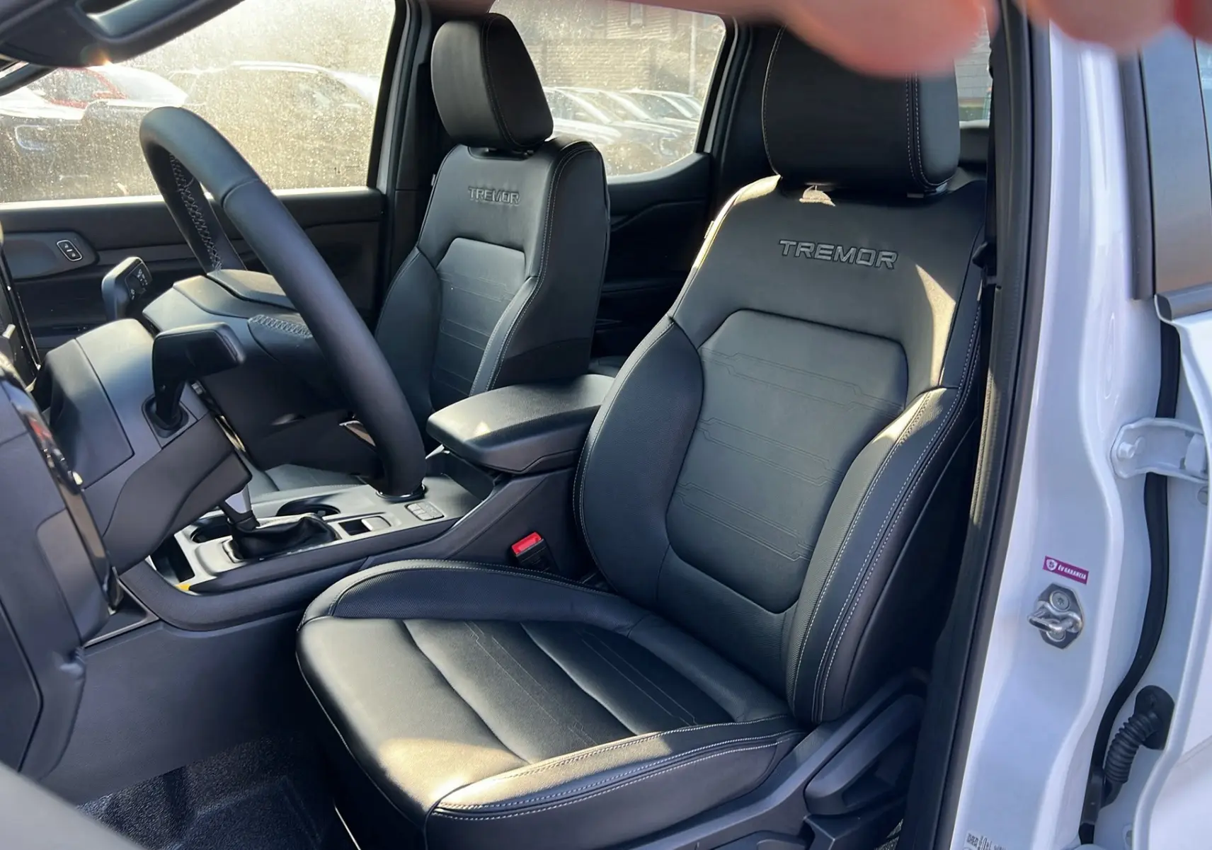 Vue intérieure côté gauche du Ford Ranger blanc glacier 2025, sièges en cuir noir avec logo Tremor brodé.