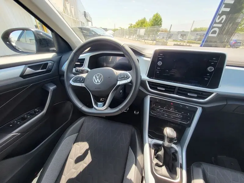 Vue intérieure du poste de conduite du Volkswagen T-Roc 2025, avec volant multifonction et écran tactile central.