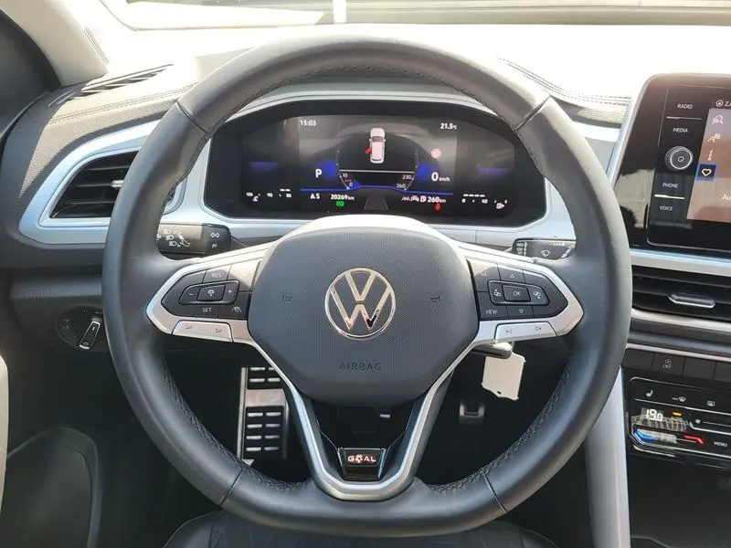 Vue intérieure centrée sur le volant noir du Volkswagen T-Roc 2025 avec tableau de bord numérique et commandes au volant.