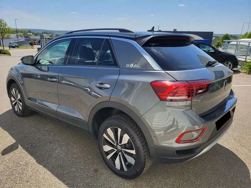 Vue 3/4 arrière droite du Volkswagen T-Roc gris Indium avec attelage amovible et jantes distinctives.