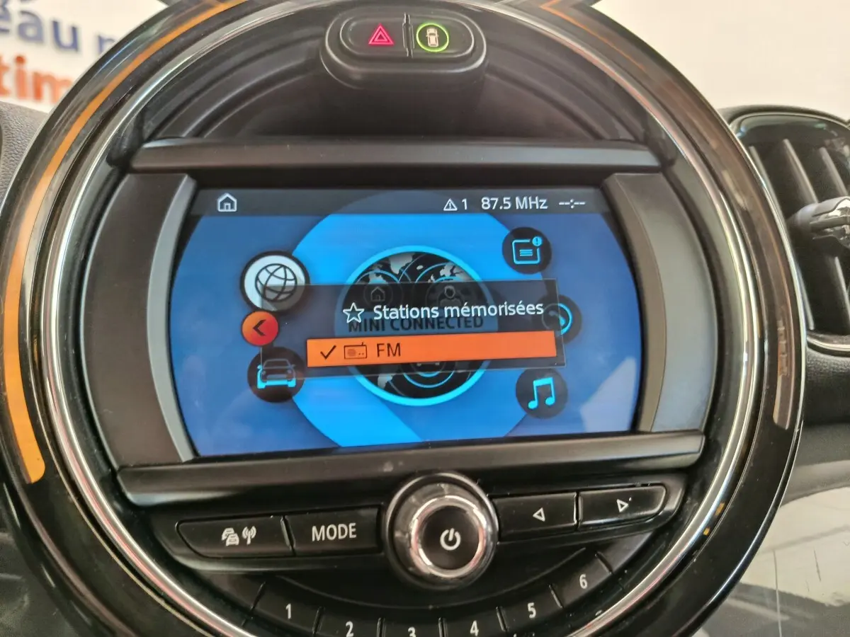 Gros plan sur l'écran central rond du MINI Countryman noir 2019 affichant le menu radio FM et commandes autour.