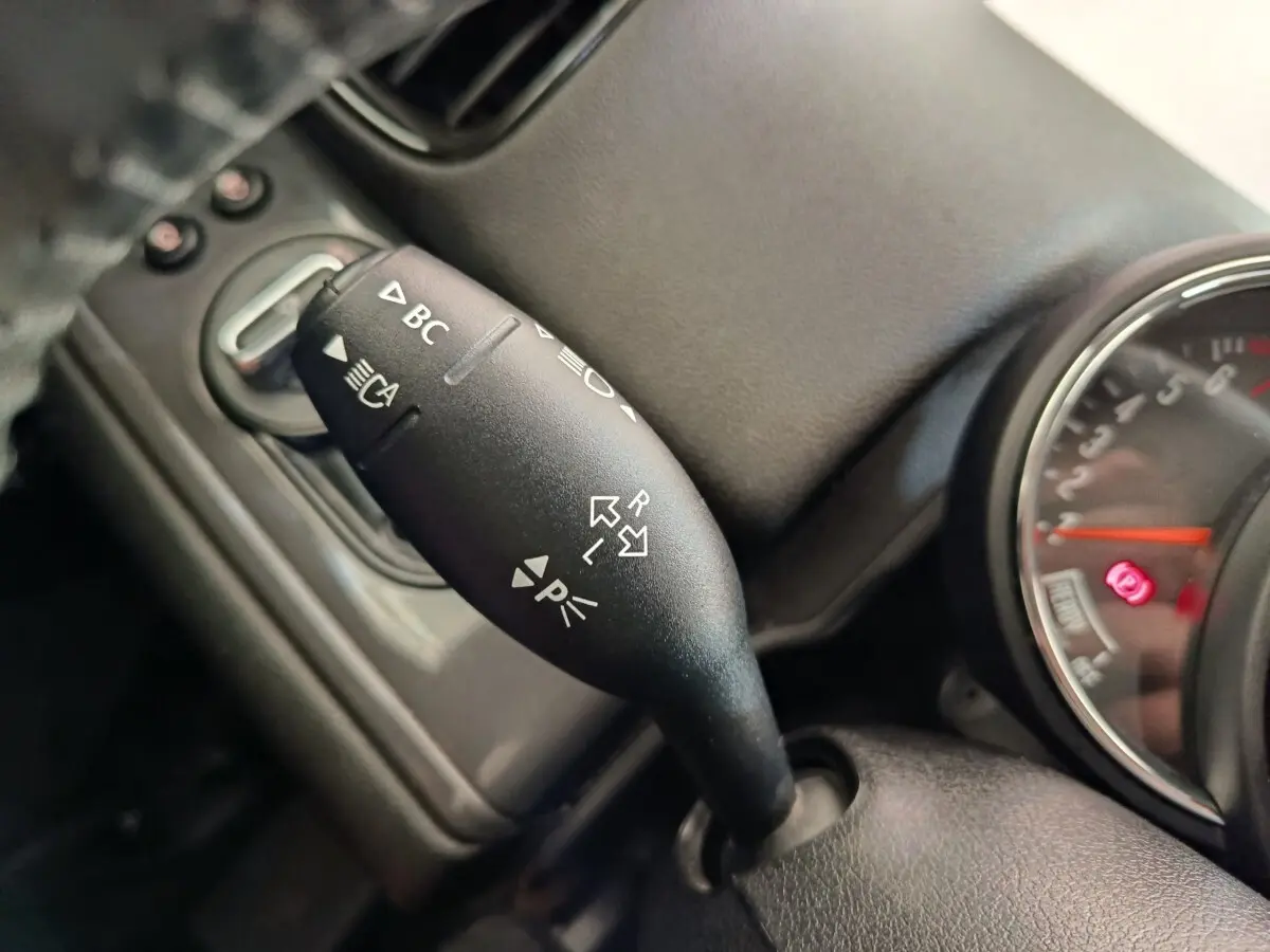 Gros plan sur la manette de clignotant et commandes au volant d'une MINI Countryman noire, tableau de bord partiellement visible.