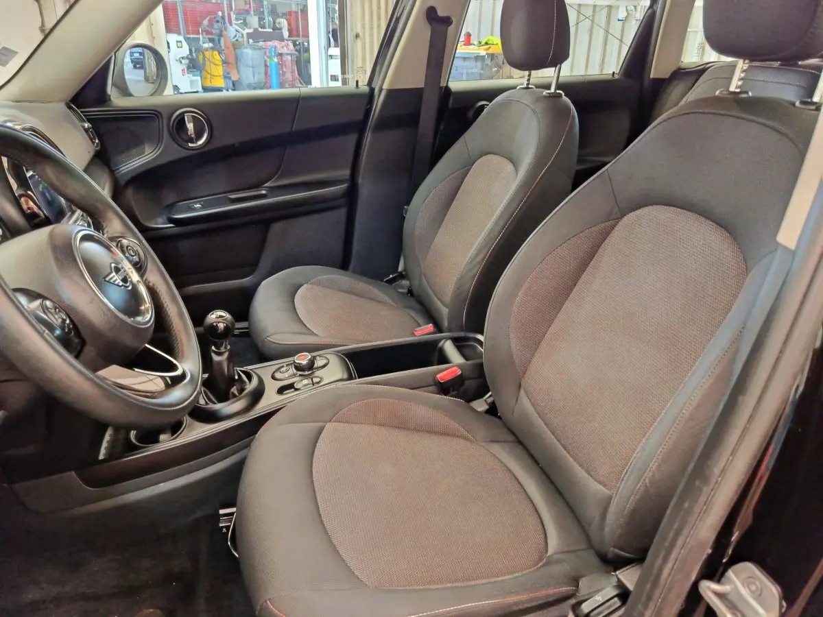 Vue intérieure côté conducteur du MINI Countryman noir 2019, montrant les sièges avant et le volant cuir multi-fonctions.