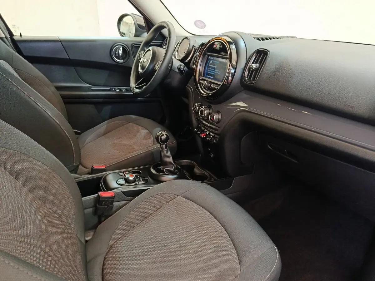 Intérieur avant droit du MINI Countryman noir 2019, tableau de bord avec écran central rond et boîte manuelle.