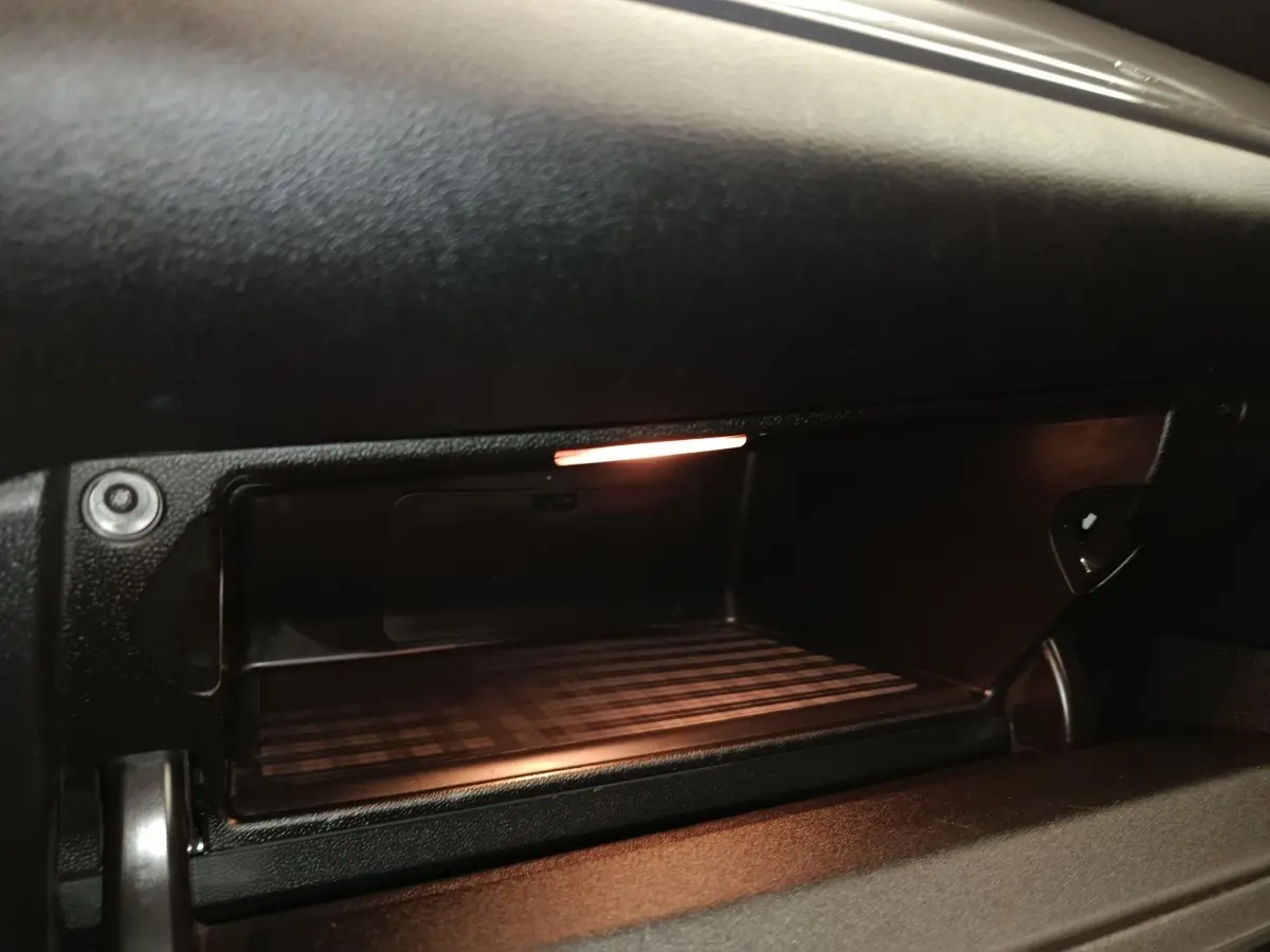 Gros plan sur la boîte à gants ouverte avec éclairage intérieur dans le tableau de bord noir du MINI Countryman 2019.
