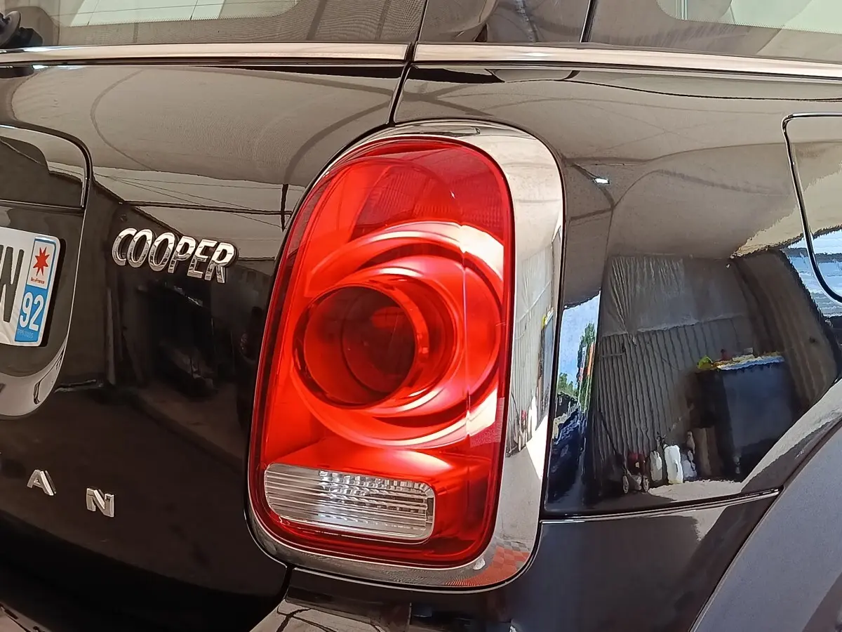 Gros plan sur le feu arrière droit rouge et l’inscription Cooper du coffre d’un MINI Countryman noir.