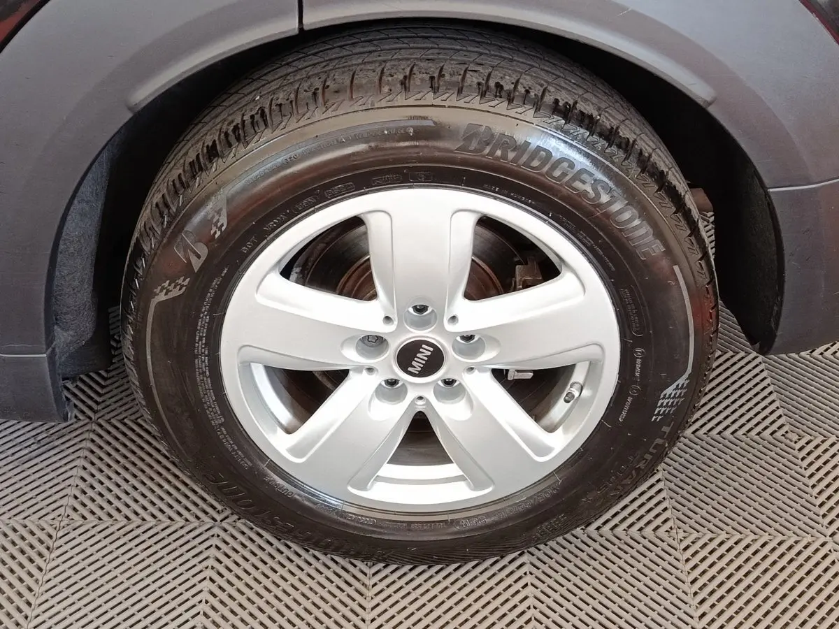 Gros plan sur la roue avant droite argentée d’une MINI Countryman noire, avec pneu Bridgestone visible.