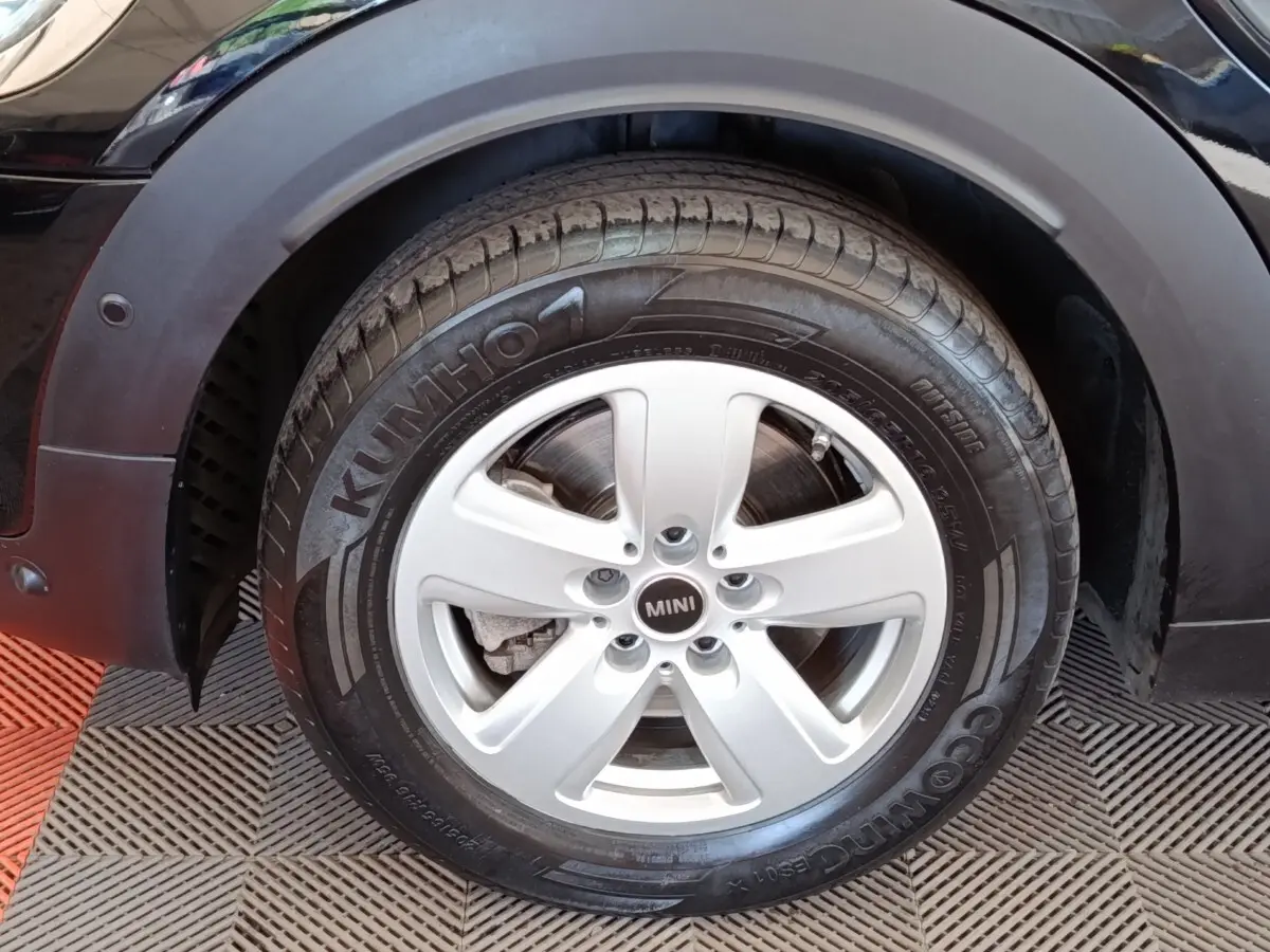 Gros plan sur la roue avant gauche d’une MINI Countryman noire, jante argentée à 5 branches et pneu Kumho.