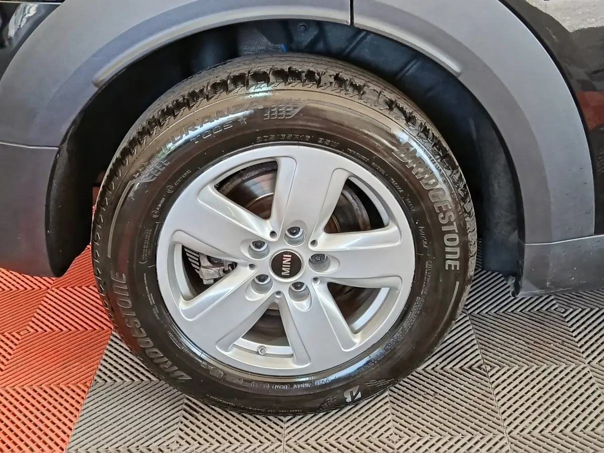 Gros plan sur la roue avant droite d'une MINI Countryman noire, jante argentée à cinq branches, pneu Bridgestone.