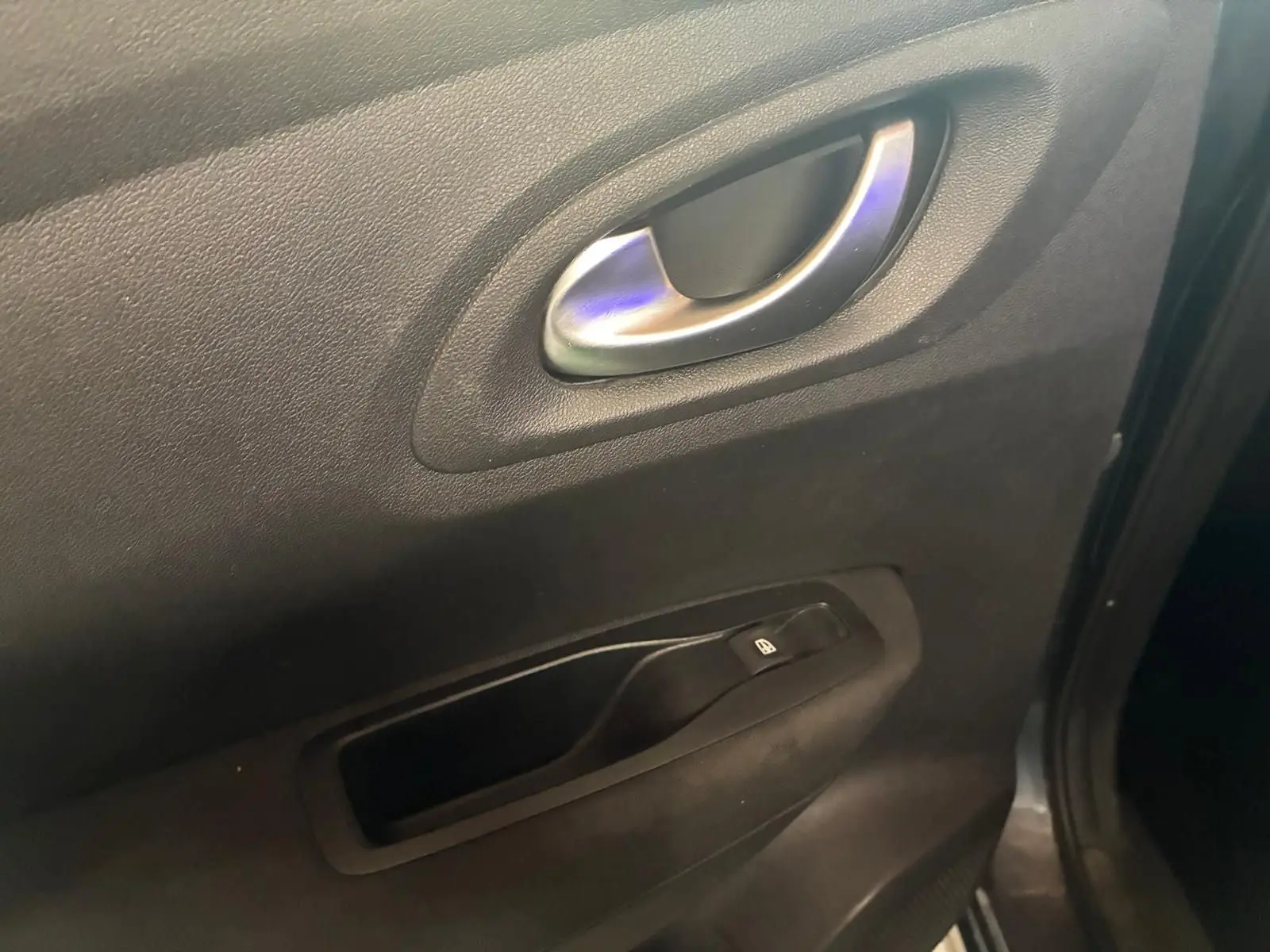 Poignée intérieure de porte côté gauche en tissu noir sur Renault Kadjar gris, version 2019, avec bouton de commande de vitre.