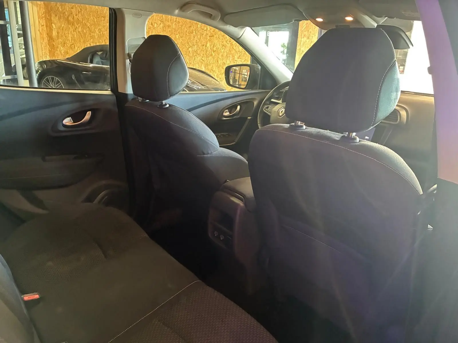 Vue intérieure arrière du Renault Kadjar gris 2019, montrant les sièges en tissu noir et la console centrale.