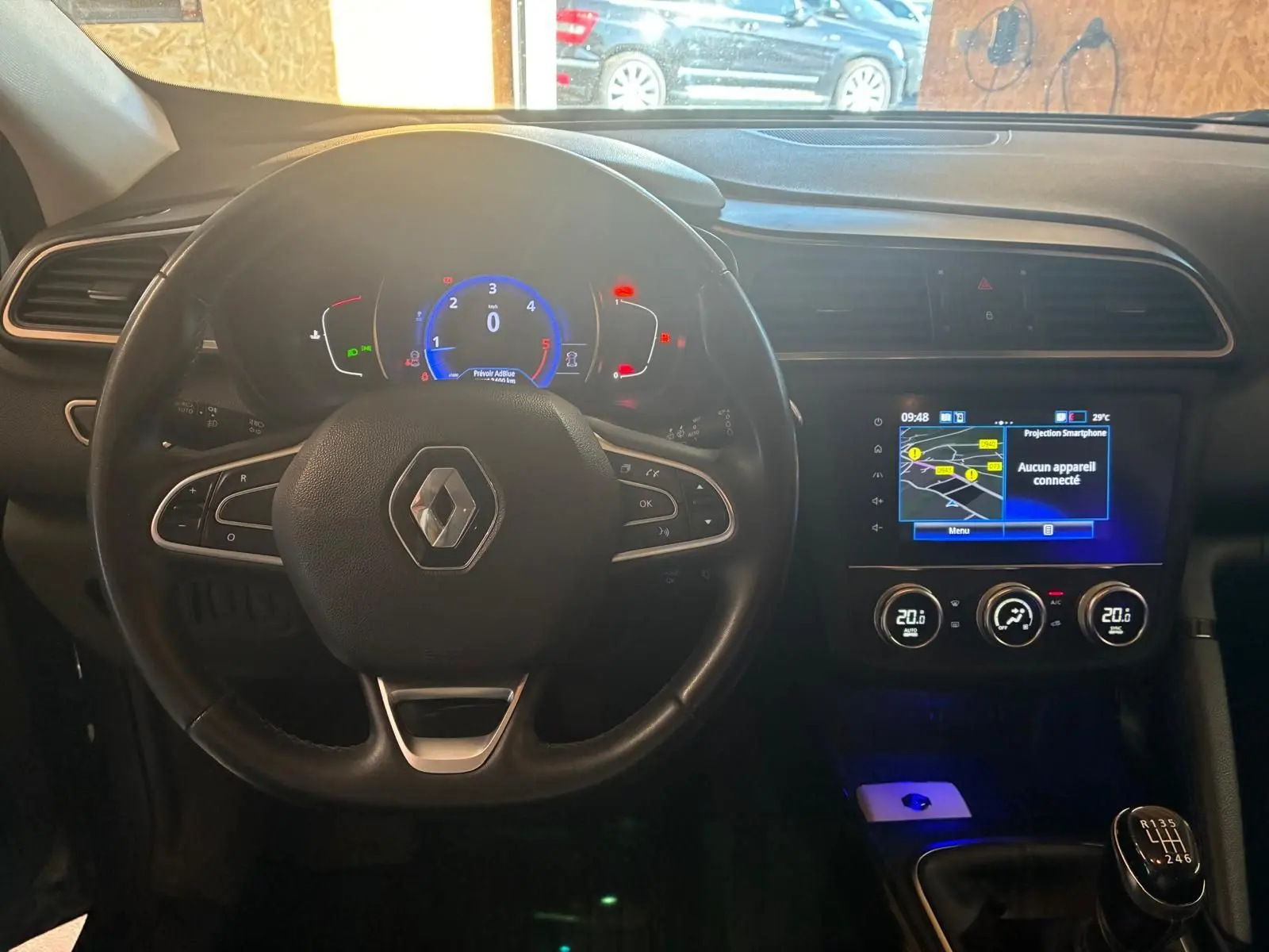 Vue intérieure centrée sur le volant Renault et le tableau de bord avec écran tactile et levier de vitesses manuel.