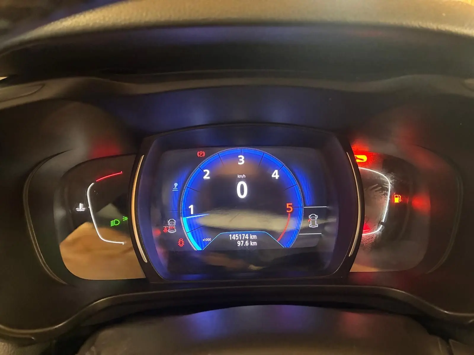 Vue rapprochée du tableau de bord numérique du Renault Kadjar 1.5 BlueDCI 115, affichage bleu et indicateurs rouges allumés.