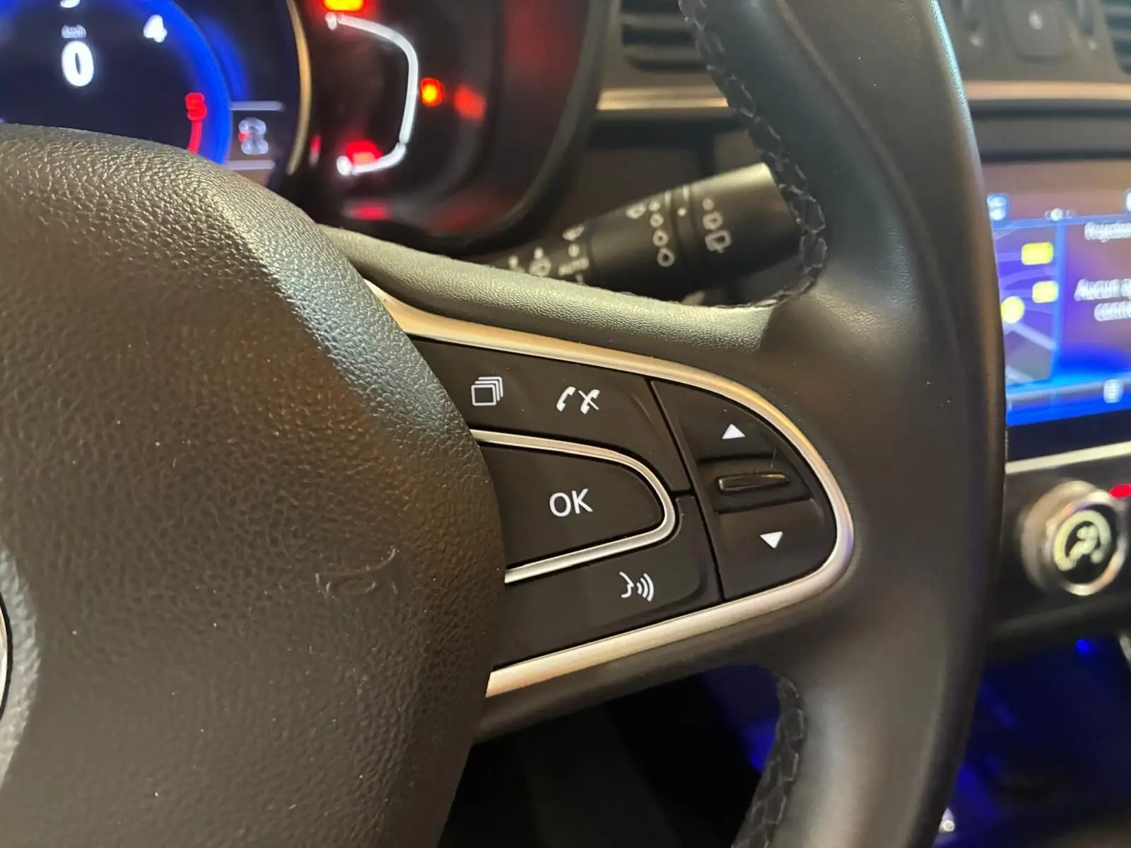 Gros plan sur la partie droite du volant noir du Renault Kadjar 2019 avec commandes multifonctions et tableau de bord éclairé.