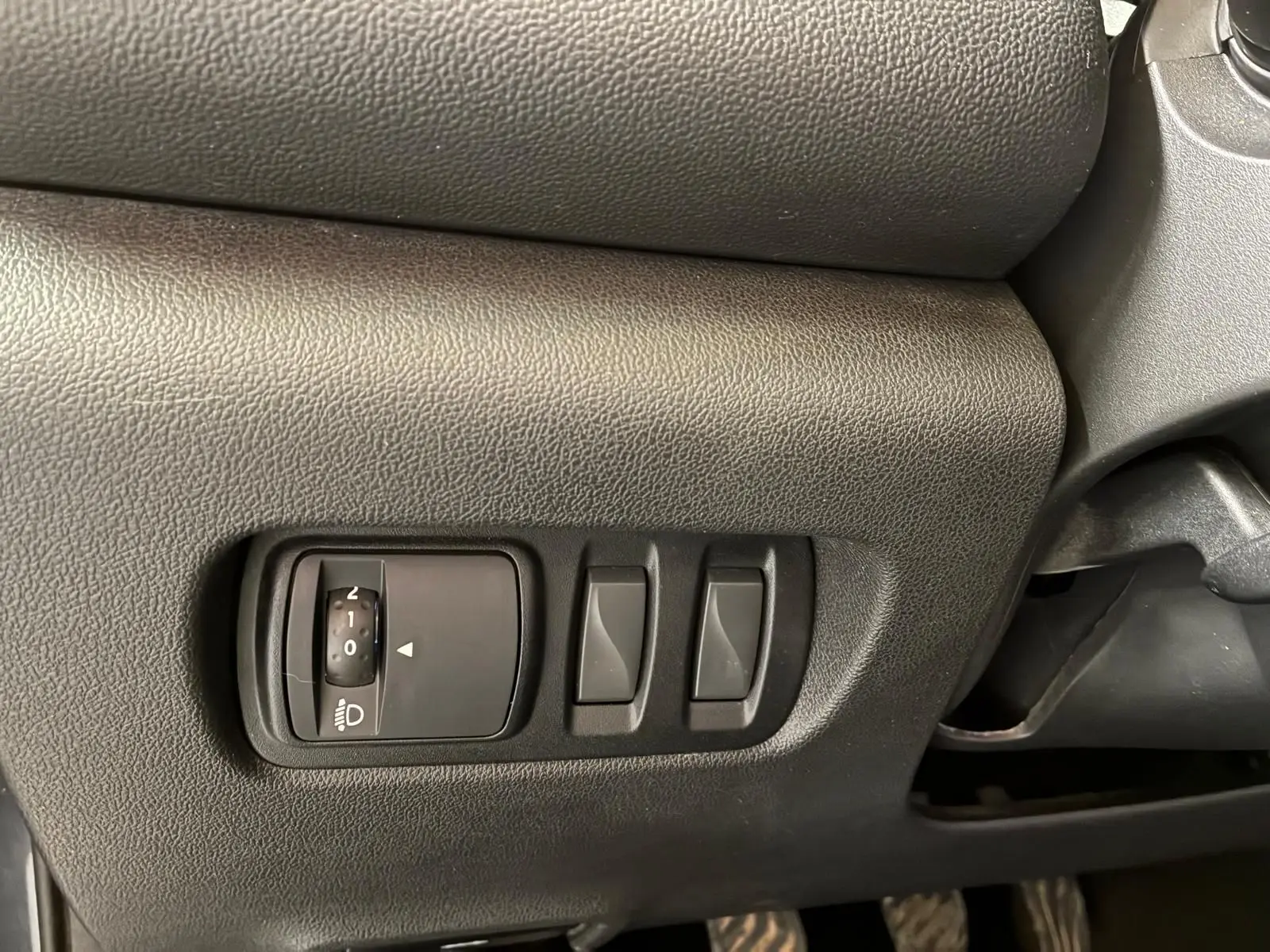 Gros plan sur les commandes de réglage des phares et des rétroviseurs côté conducteur du Renault Kadjar gris 2019.