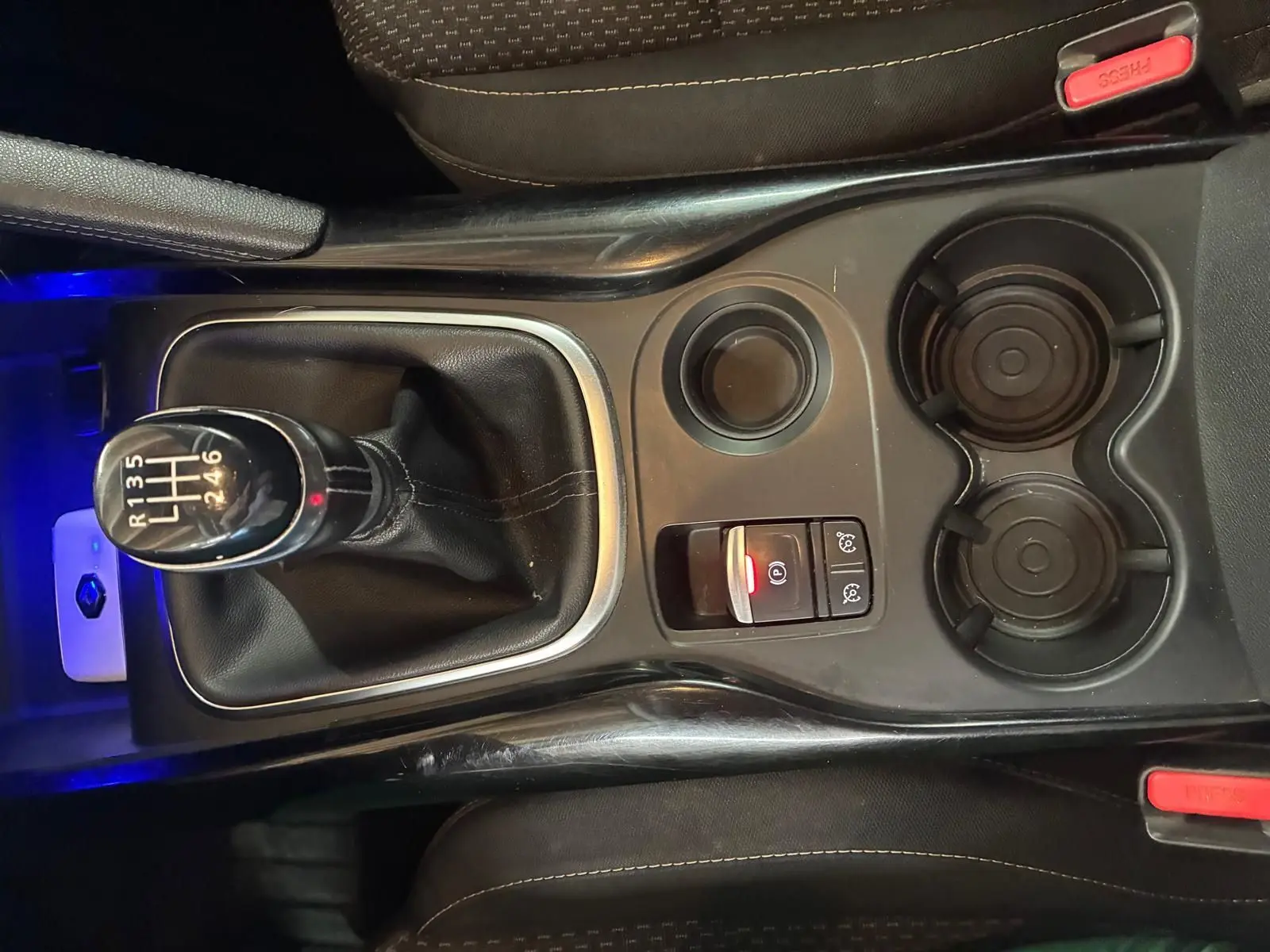 Vue plongeante sur la console centrale du Renault Kadjar gris, mettant en valeur le levier de vitesses manuel et les porte-gobelets.