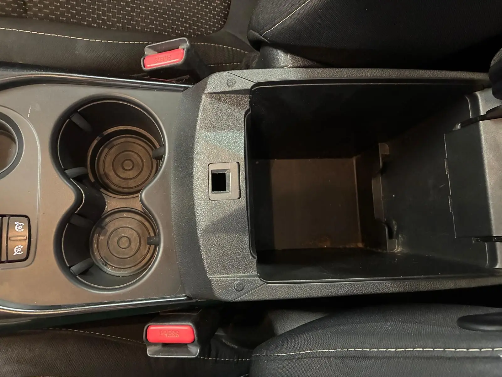Vue plongeante sur la console centrale noire du Renault Kadjar 2019, avec porte-gobelets et rangement ouvert.