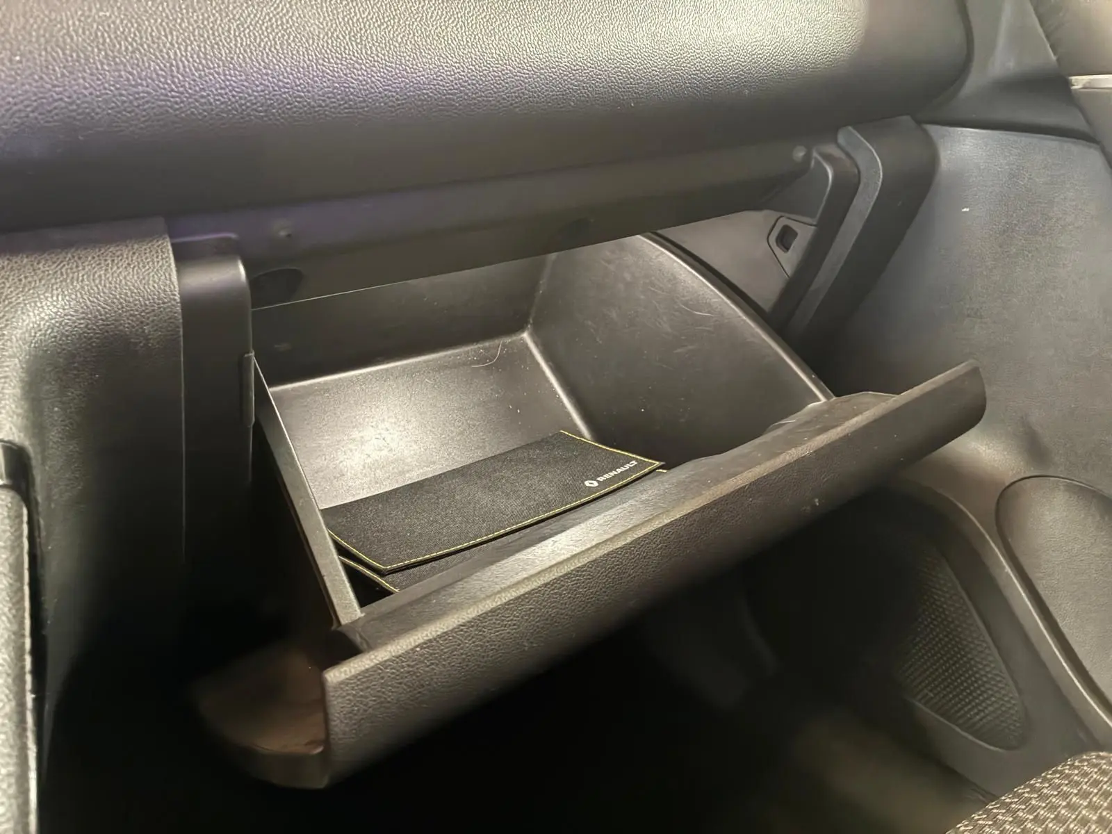 Gros plan sur la boîte à gants ouverte du Renault Kadjar 2019, intérieur noir avec manuel de bord visible.