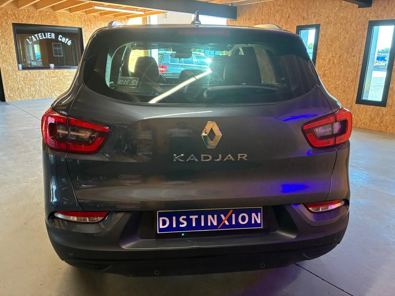 Vue arrière d’un Renault Kadjar gris 2019 avec feux arrière allumés et plaque DISTINXION visible en intérieur.