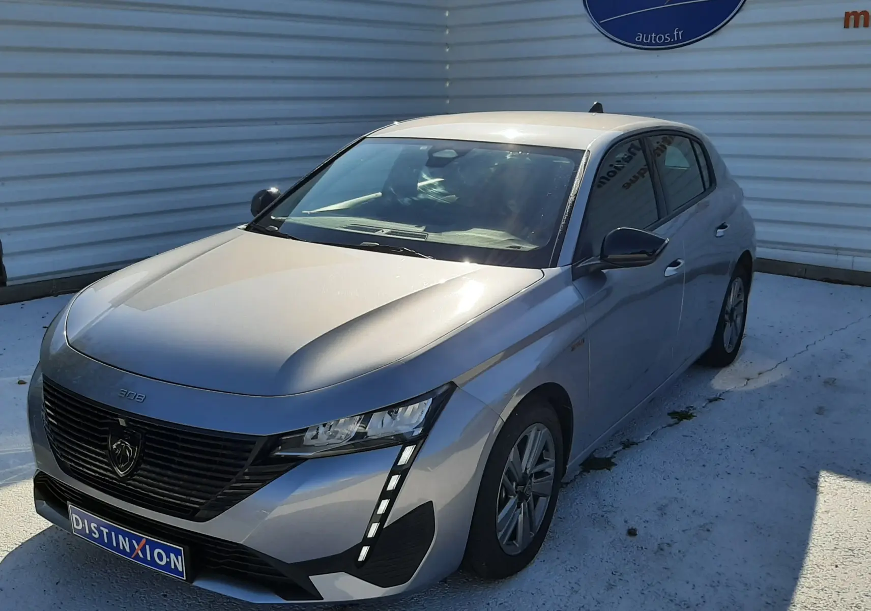 Peugeot 308 III Hybrid gris Artense vue 3/4 avant droit, avec calandre noire et feux LED verticaux distinctifs.