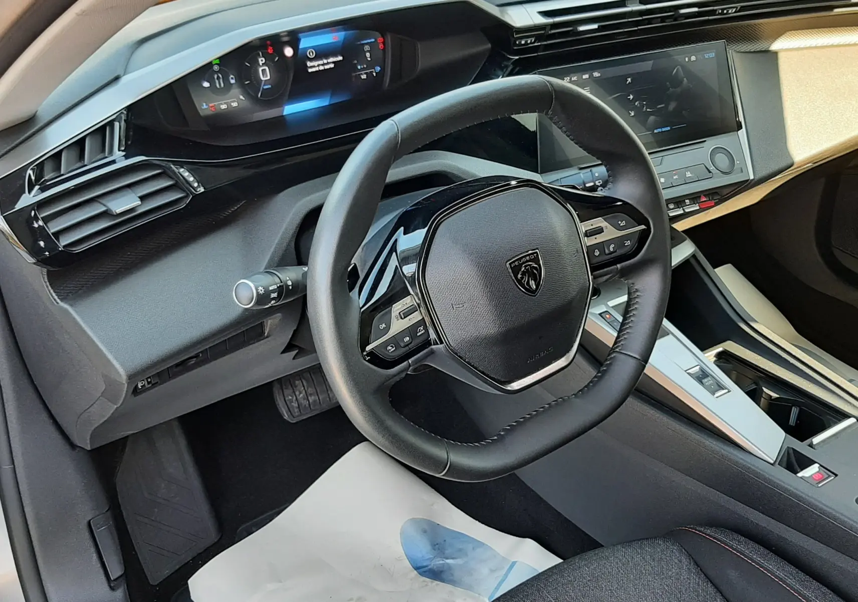 Vue intérieure côté conducteur du Peugeot 308 gris Artense 2025, avec tableau de bord numérique et volant multifonction noir.