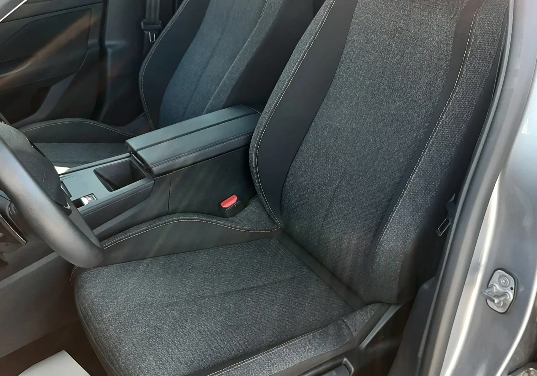 Vue intérieure côté conducteur de la Peugeot 308 III Hybrid 145ch Style 2025, siège tissu gris avec surpiqûres contrastées.