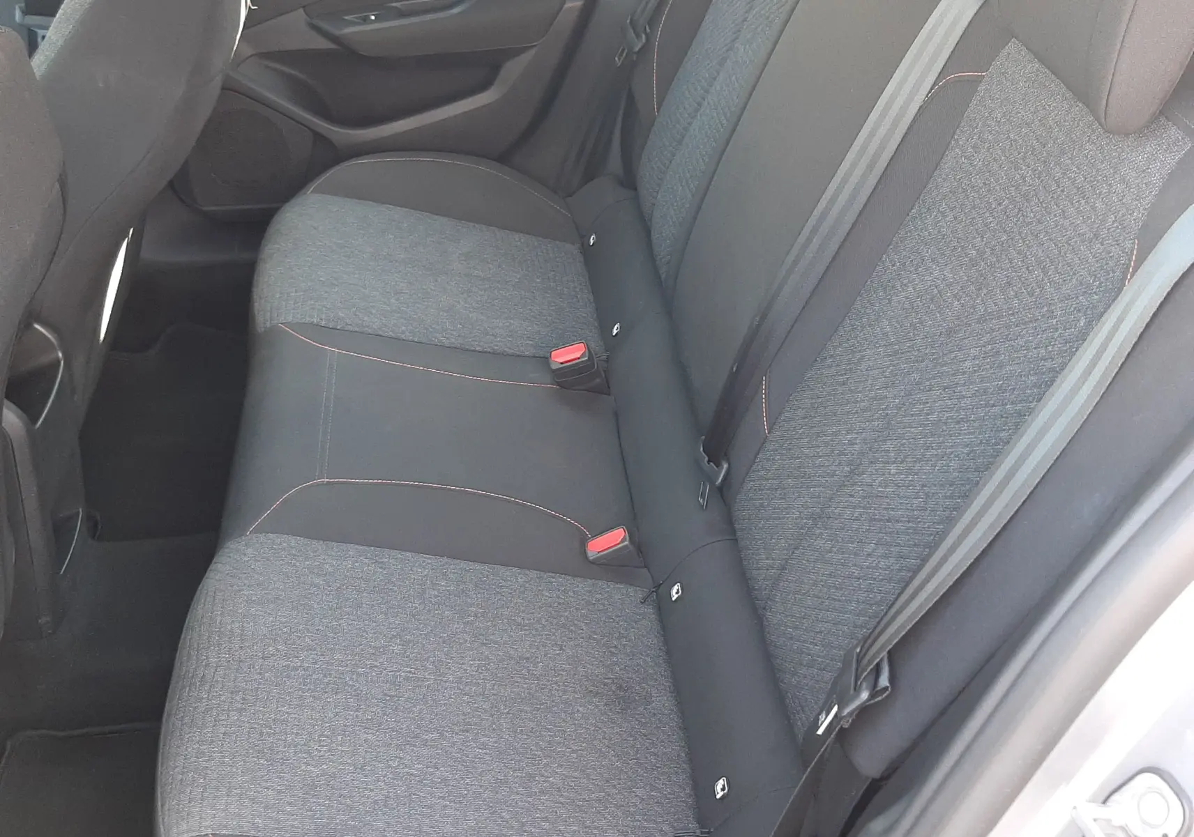 Vue intérieure côté droit des sièges arrière en tissu gris et noir avec surpiqûres rouges d'une Peugeot 308 III Hybrid 2025.