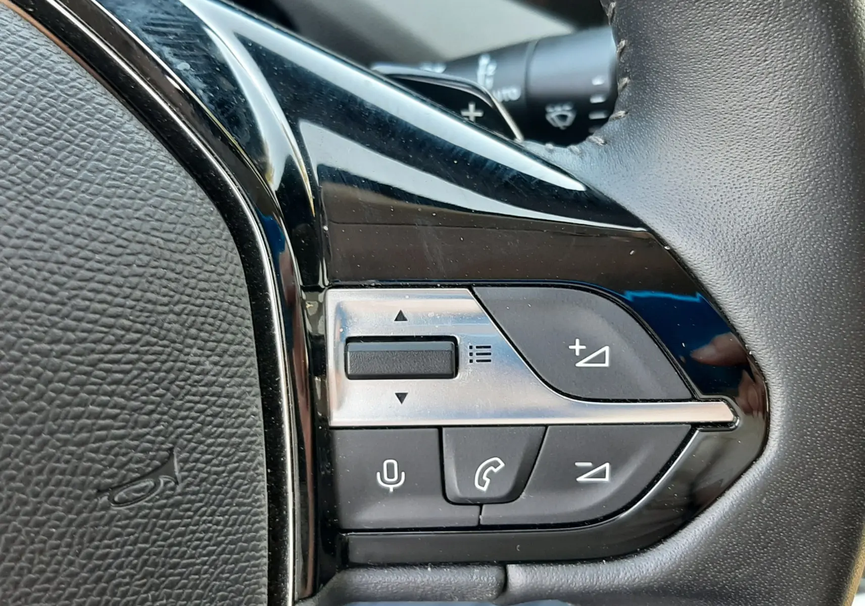Gros plan sur les commandes multifonctions à droite du volant noir de la Peugeot 308 III Hybrid 145ch Style.