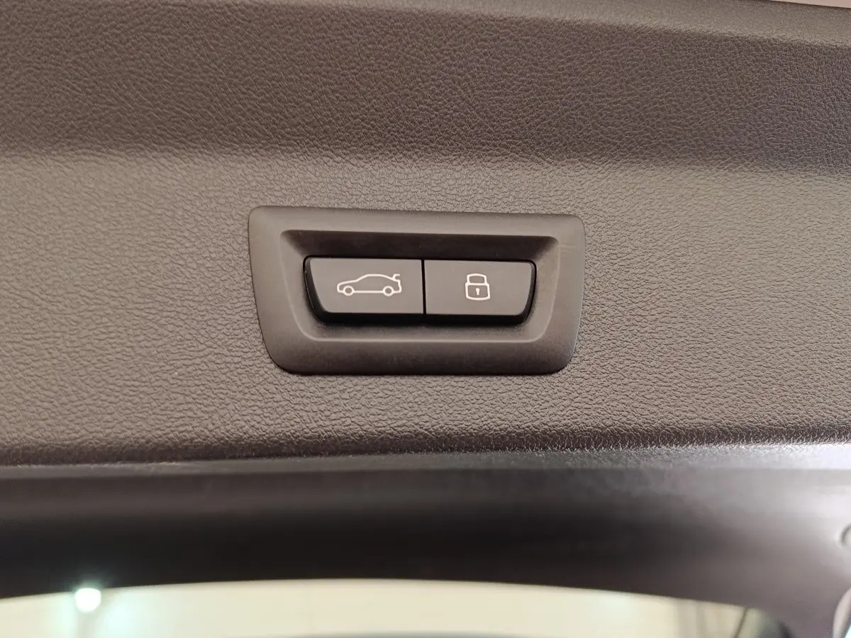 Boutons d'ouverture et de verrouillage du coffre sur la garniture intérieure d'un BMW X3 blanc hybride rechargeable.