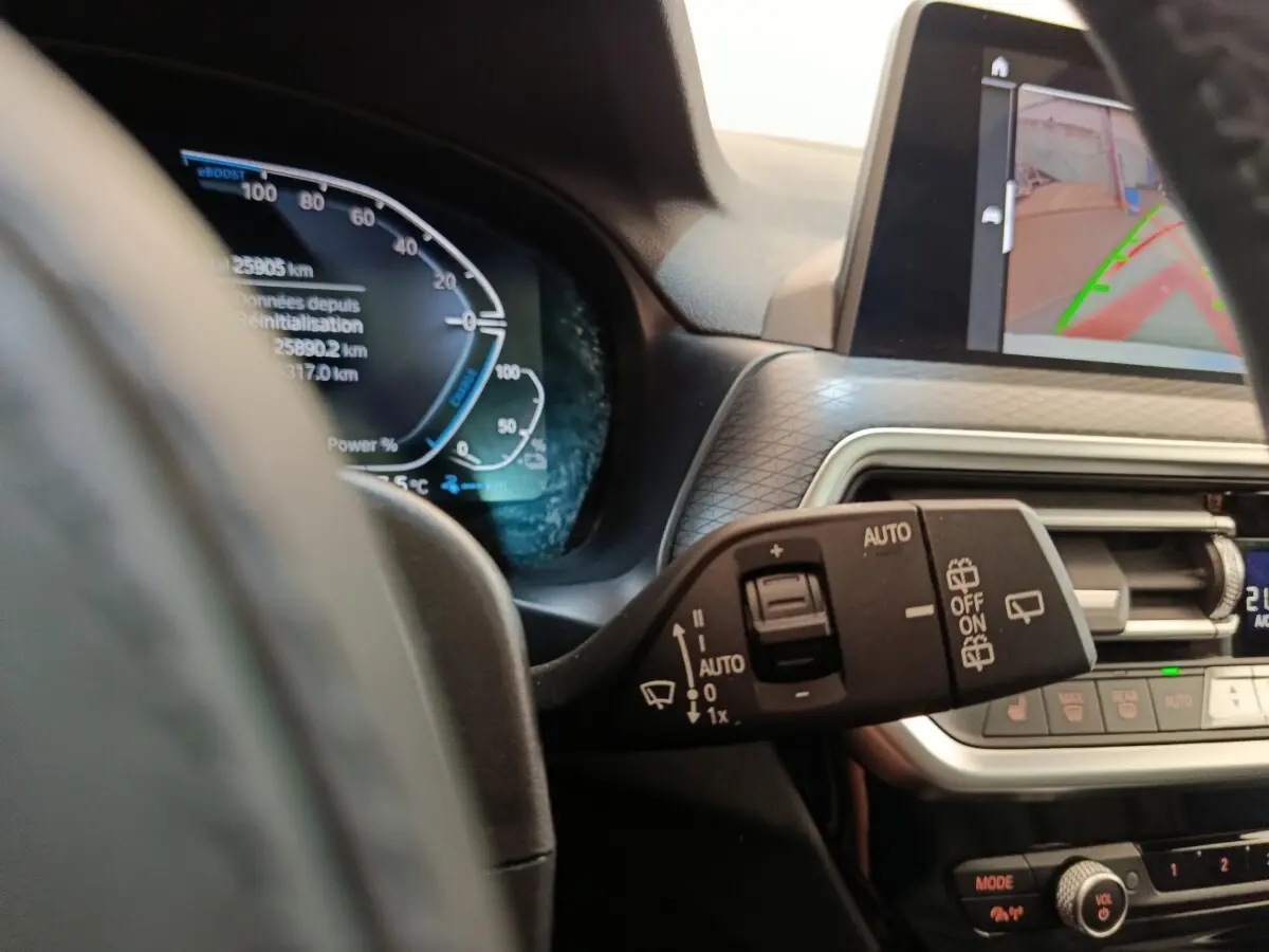 Gros plan sur le combiné d'instruments et la commande d'essuie-glace dans l'habitacle d'une BMW X3 blanche 2023.