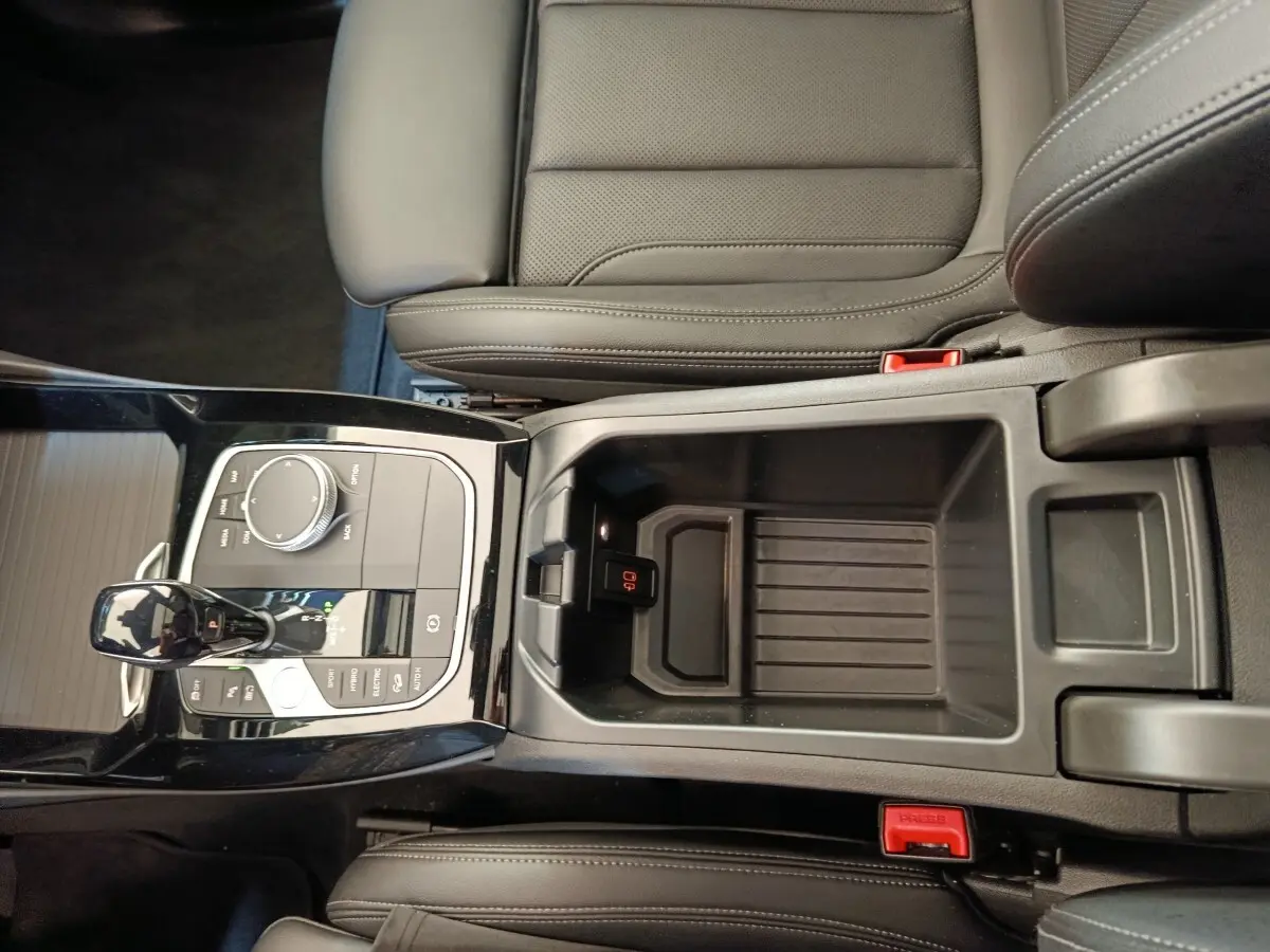 Vue plongeante sur la console centrale noire et les sièges en cuir gris foncé du BMW X3 xDrive30e 2023.