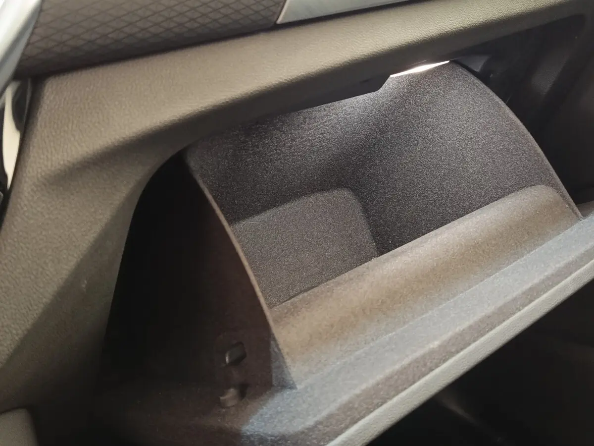 Gros plan sur la boîte à gants ouverte du BMW X3 xDrive30e blanc, montrant l'intérieur texturé noir.