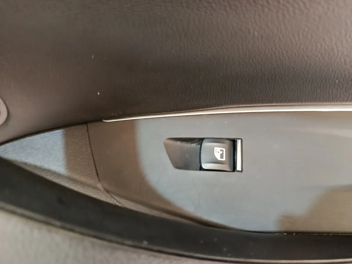 Gros plan sur le bouton de verrouillage des portes sur la garniture intérieure noire d'une BMW X3 blanche hybride rechargeable.