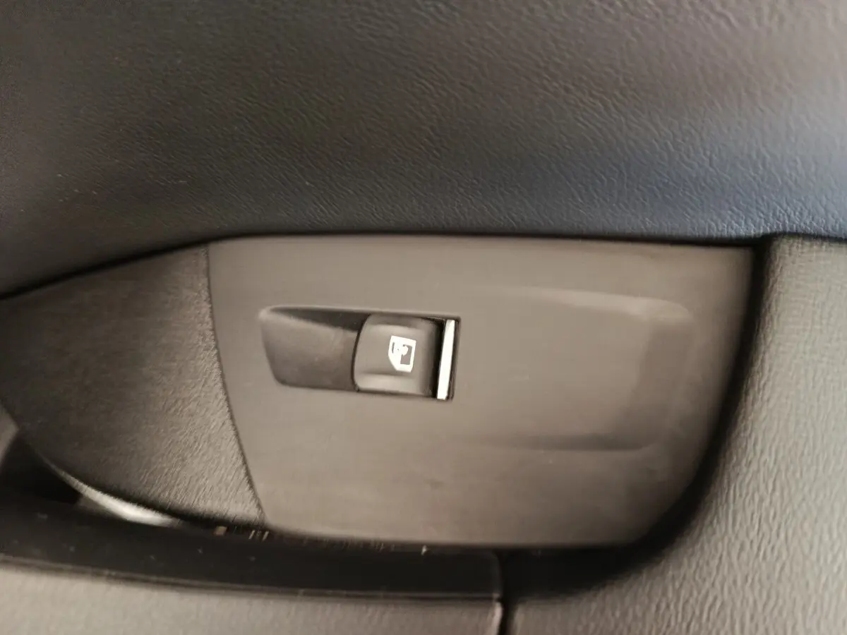 Gros plan sur le bouton d'ouverture de trappe à carburant dans l'habitacle du BMW X3 blanc xDrive30e 2023.