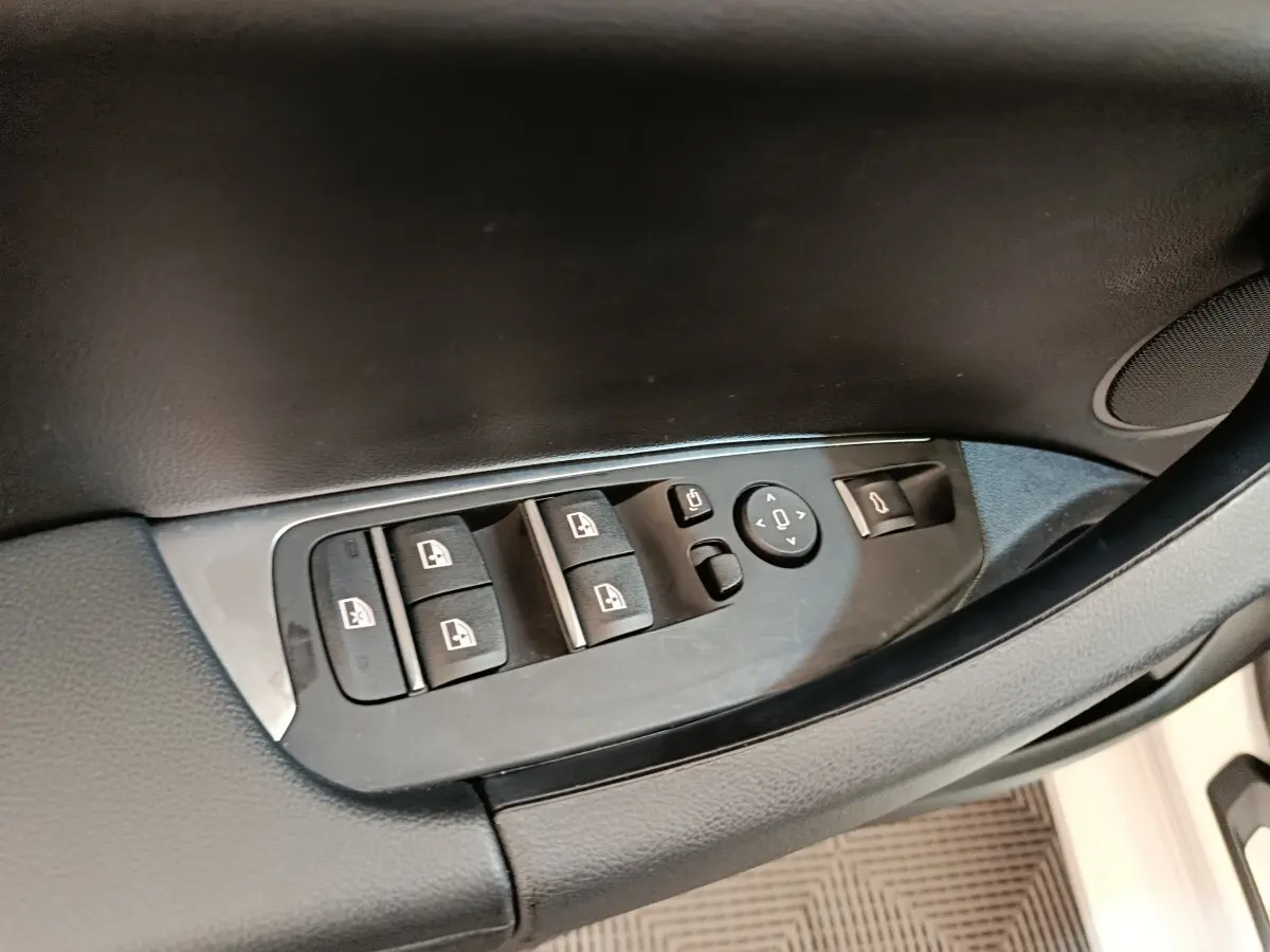 Détail des commandes de lève-vitres et rétroviseurs sur la porte côté conducteur d’un BMW X3 blanc 2023.
