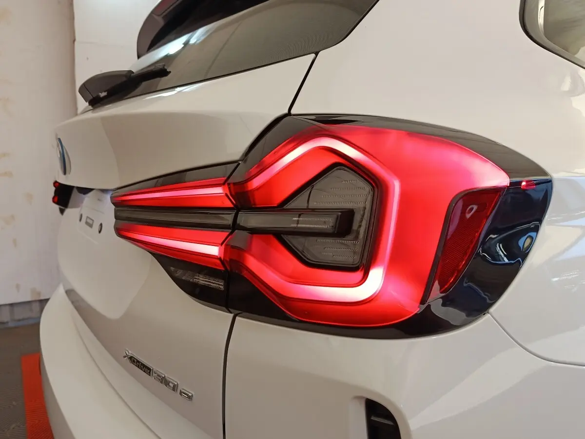Gros plan sur le feu arrière droit rouge et noir d’un BMW X3 blanc xDrive30e 2023, vue arrière côté droit.