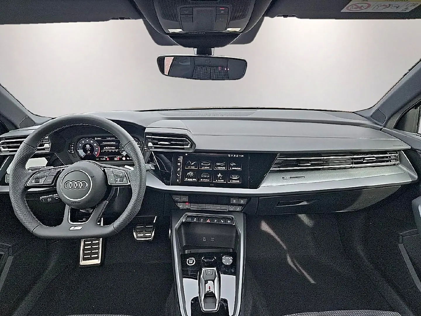Vue intérieure avant de l'Audi A3 Sportback 2026 noir mythos, volant sport multifonction et écran tactile central.