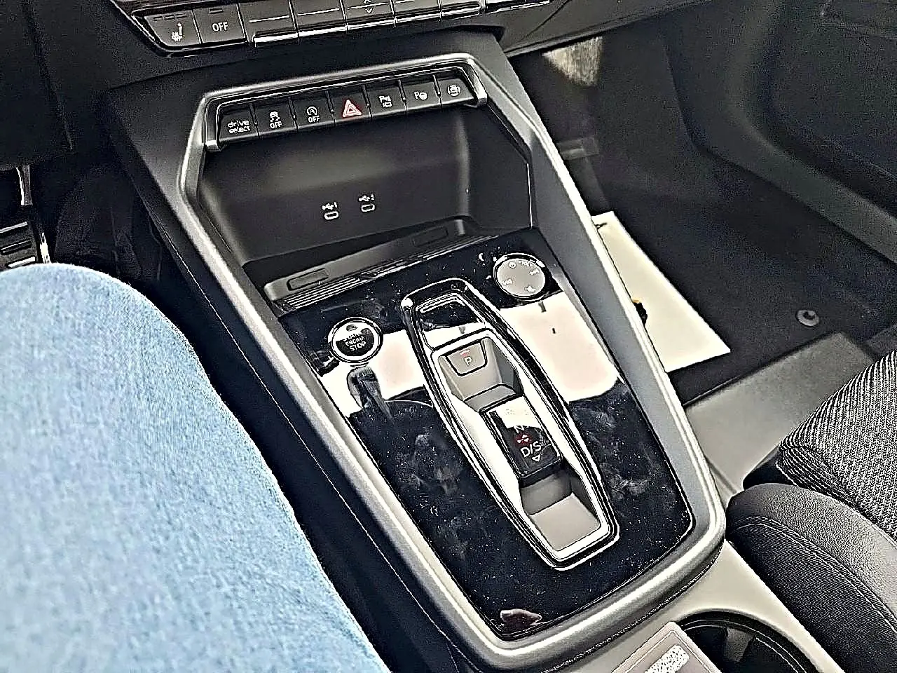 Vue rapprochée de la console centrale noire brillante de l'Audi A3 Sportback 2026 avec levier de vitesses automatique et boutons de contrôle.