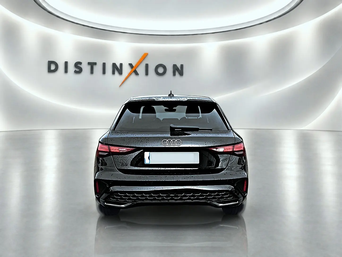 Vue arrière d'une Audi A3 Sportback noir mythos 2026 avec feux arrière LED et becquet intégré, en studio lumineux.