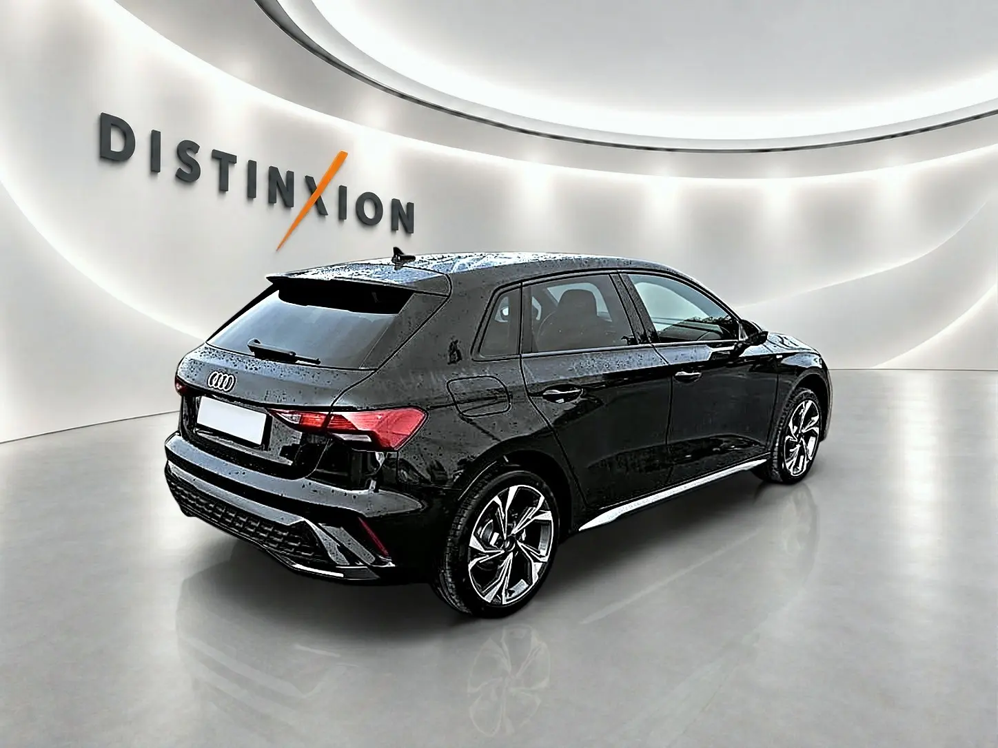 Audi A3 Sportback noir mythos vue 3/4 arrière droit dans un showroom lumineux avec jantes alu distinctives.