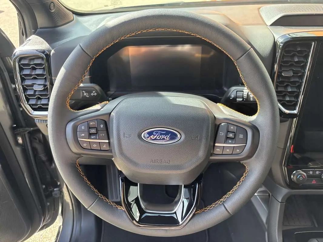 Vue rapprochée du volant en cuir noir avec surpiqûres marron du Ford Ranger gris carbone 2026, tableau de bord partiel visible.