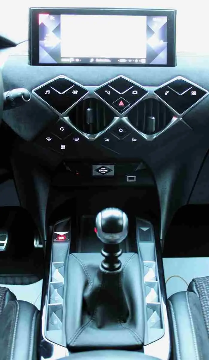 Vue intérieure centrée sur la console centrale noire du DS3 Crossback 2021 avec levier de vitesse manuel et écran tactile.