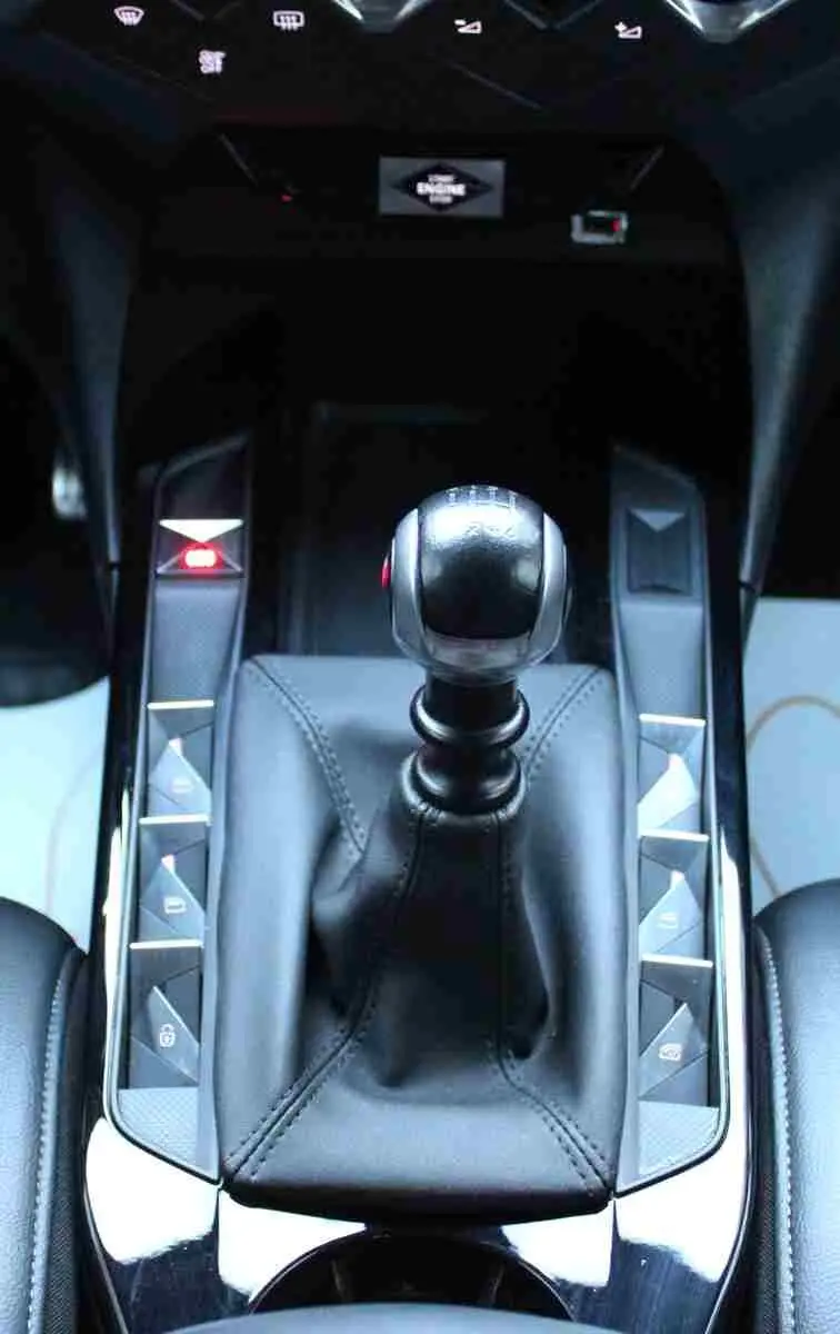 Vue rapprochée du levier de vitesse manuel en cuir noir du DS3 Crossback, entouré de boutons de commande brillants.