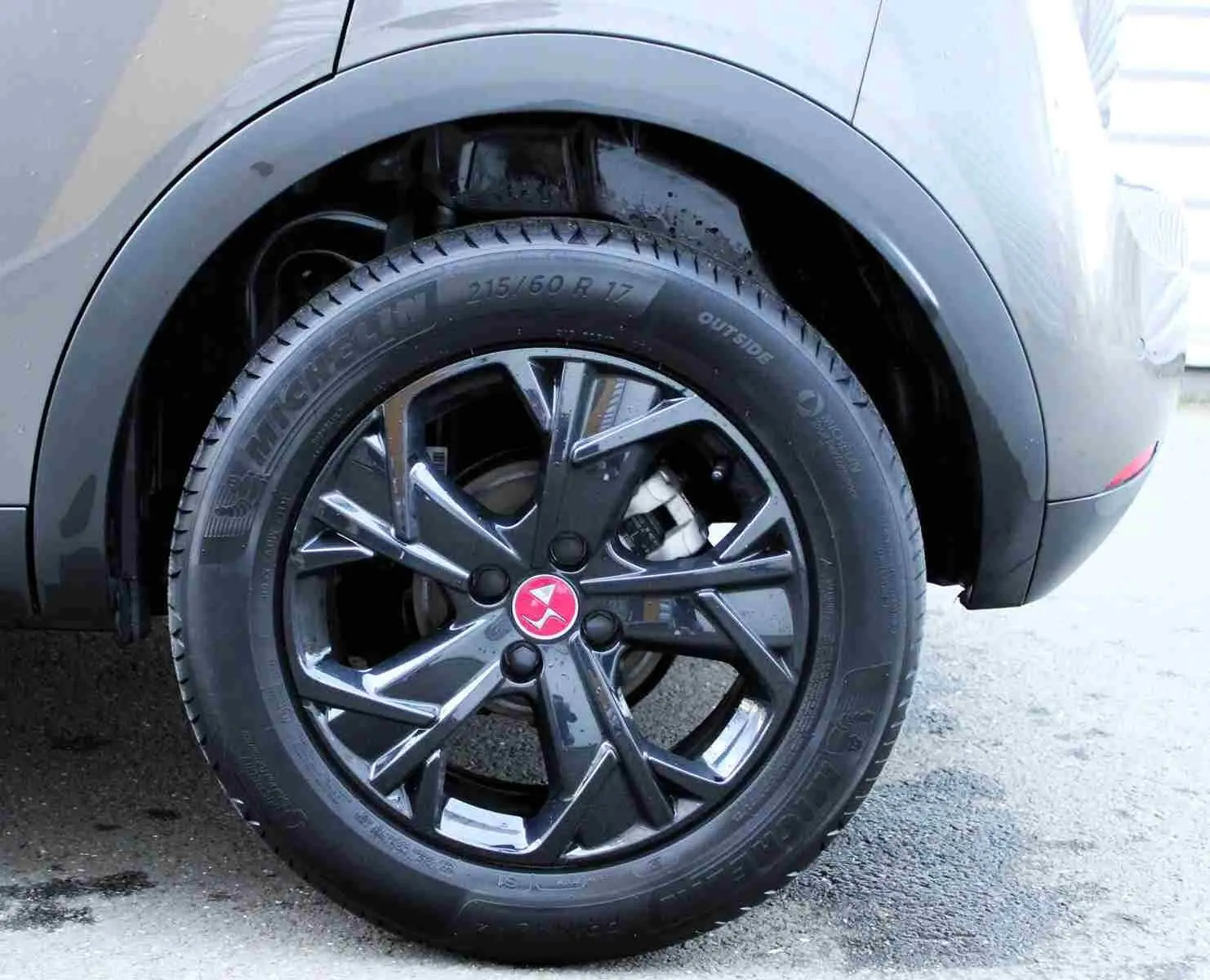 Gros plan sur la roue arrière droite du DS3 Crossback gris platinium avec jante noire brillante et logo rouge au centre.