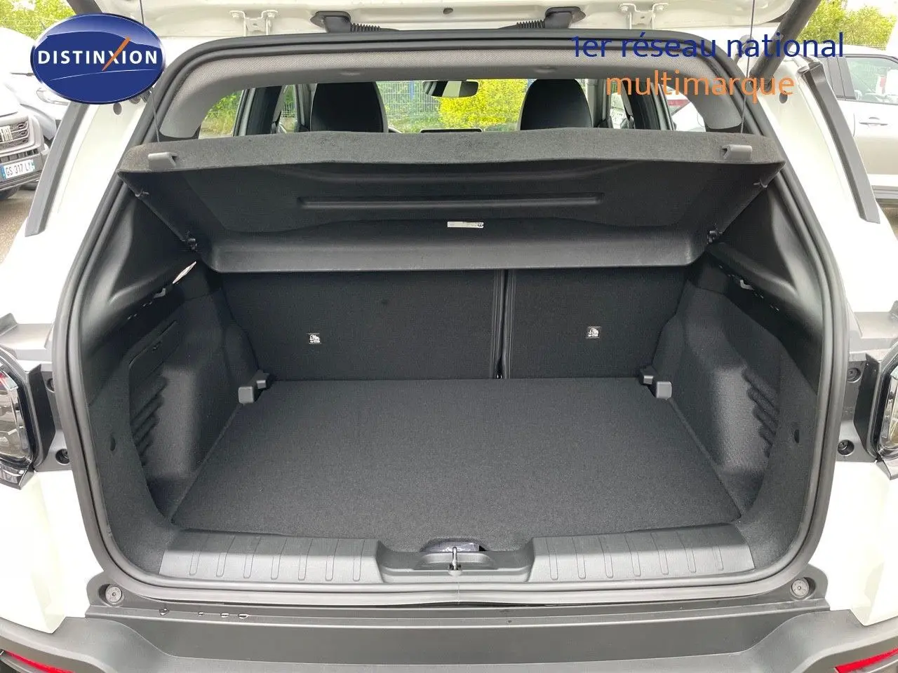 Coffre ouvert d'un Jeep Avenger blanc neige 2024, vue arrière montrant l'espace de chargement vide et la plage arrière relevée.