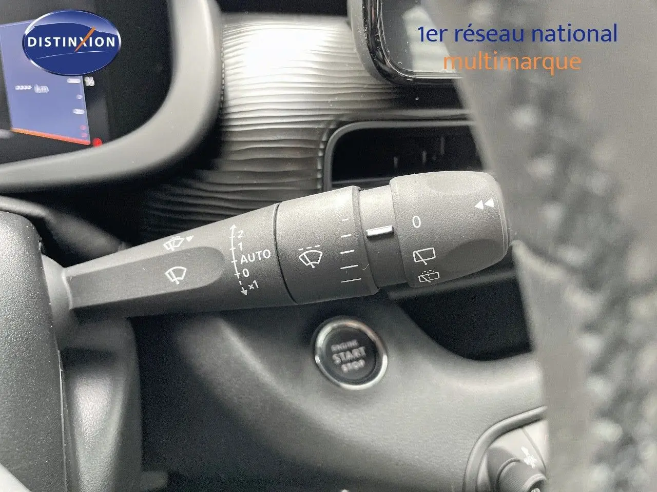 Gros plan sur la commande d'essuie-glace et le bouton start/stop du tableau de bord d'une Jeep Avenger blanc neige 2024.