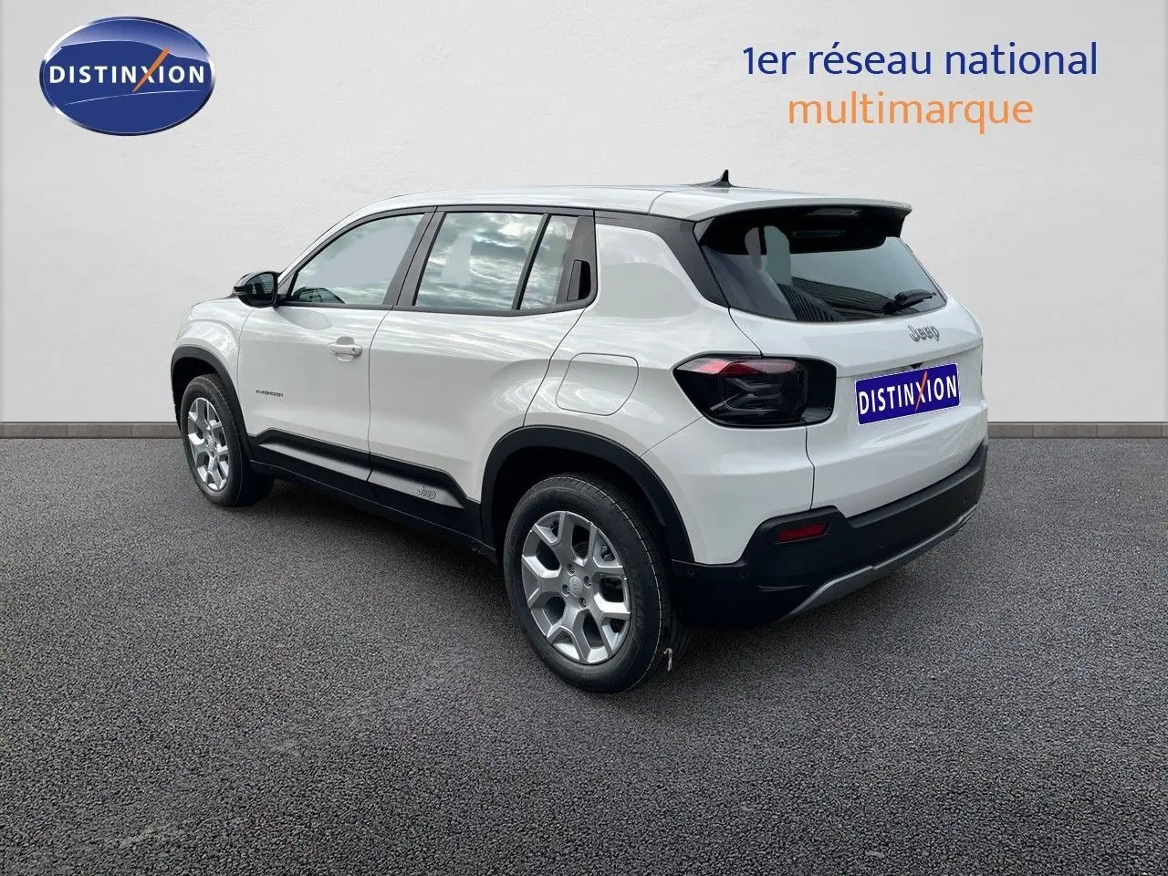 Jeep Avenger blanc neige vu de trois quarts arrière droit, avec jantes argentées et feux arrière noirs.