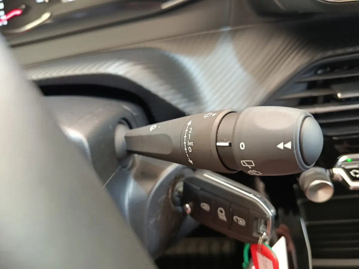 Gros plan sur la commande d’essuie-glace côté gauche du tableau de bord d’une Peugeot 208 blanche 2023.