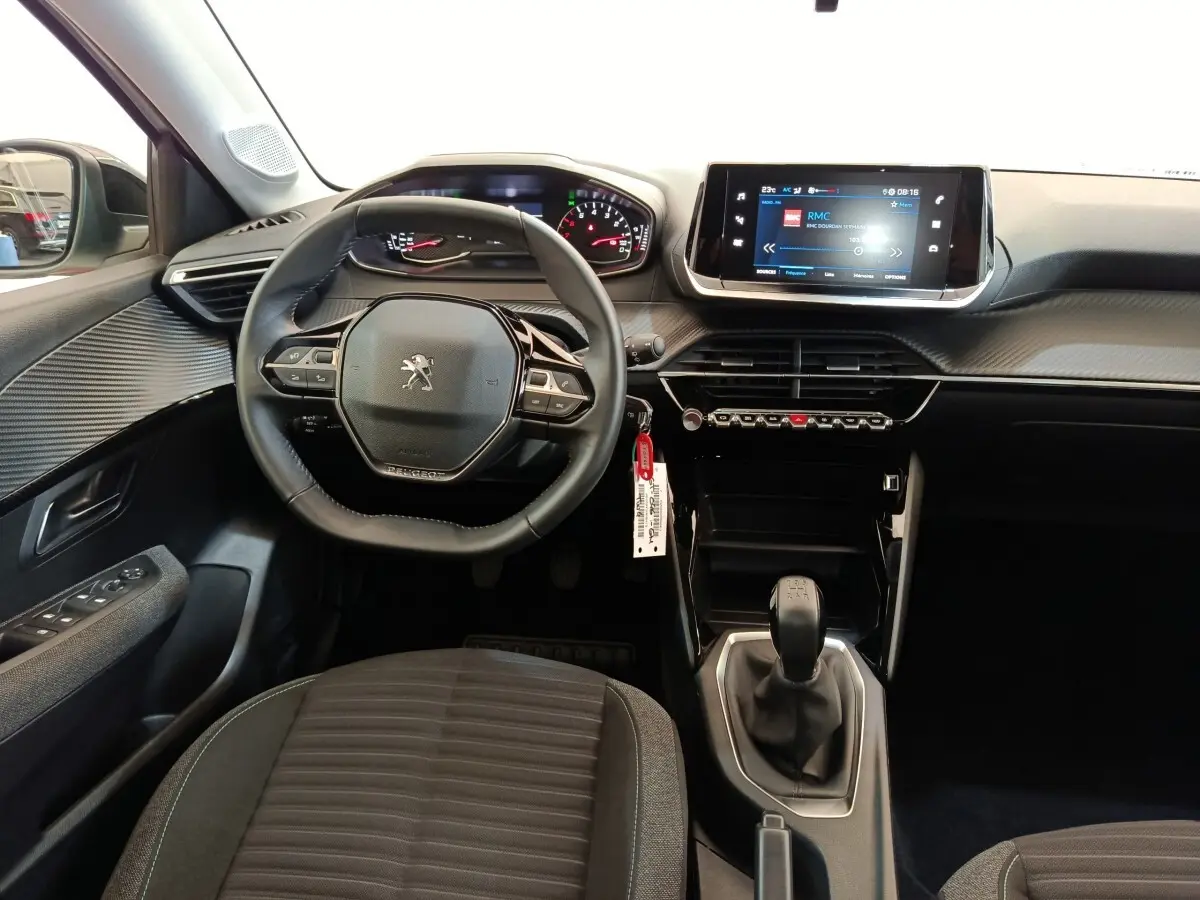Vue intérieure avant centrée sur le volant cuir et la console centrale avec écran tactile de la Peugeot 208 PureTech 75 S&S Style.